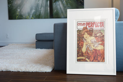 Mucha Cycles Perfecta poster leaning beside a blue sofa