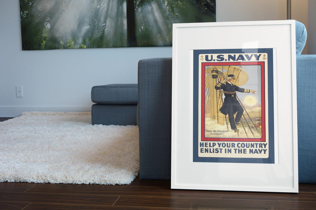Damn the Torpedoes Enlist in the Navy poster leaning beside a blue sofa