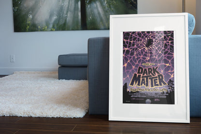 Dark Matter, NASA Galaxy of Horrors poster in a white frame leaning beside a blue sofa