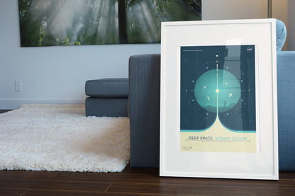 Deep Space Atomic Clock, teal poster in a white frame leaning beside a blue sofa