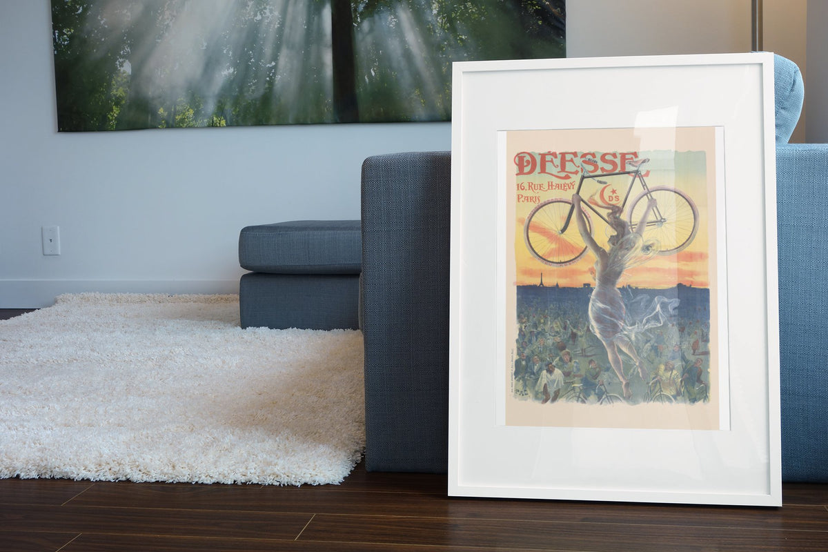 Deesse Bicycles Paris poster leaning beside a blue sofa