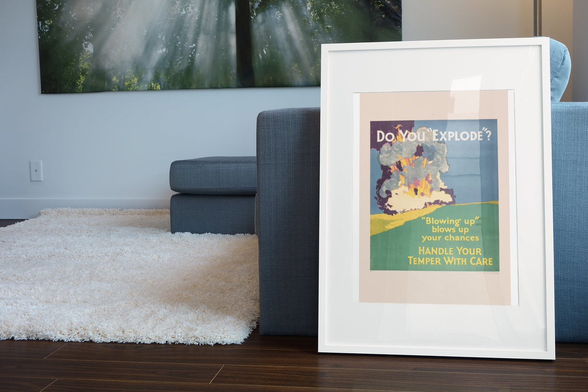 Do You “Explode” poster in a white frame leaning beside a blue sofa