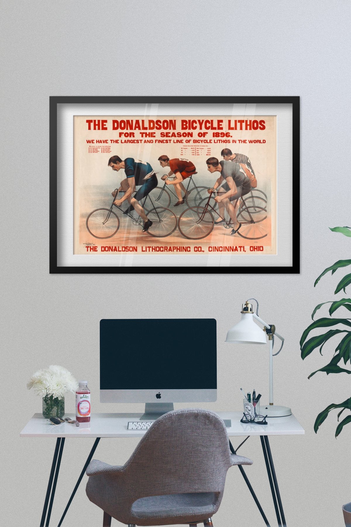Donaldson Bicycle Racing 1896 poster framed on a grey wall above a desk