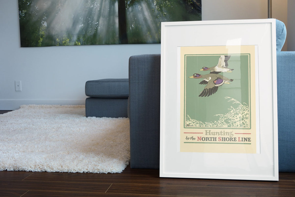 Duck Hunting — North Shore Line poster leaning beside a blue sofa