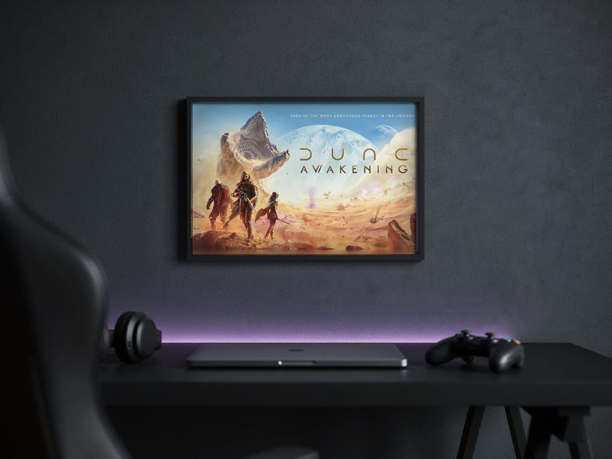 Dune: Awakening Key Art poster in a black frame above a gaming desk
