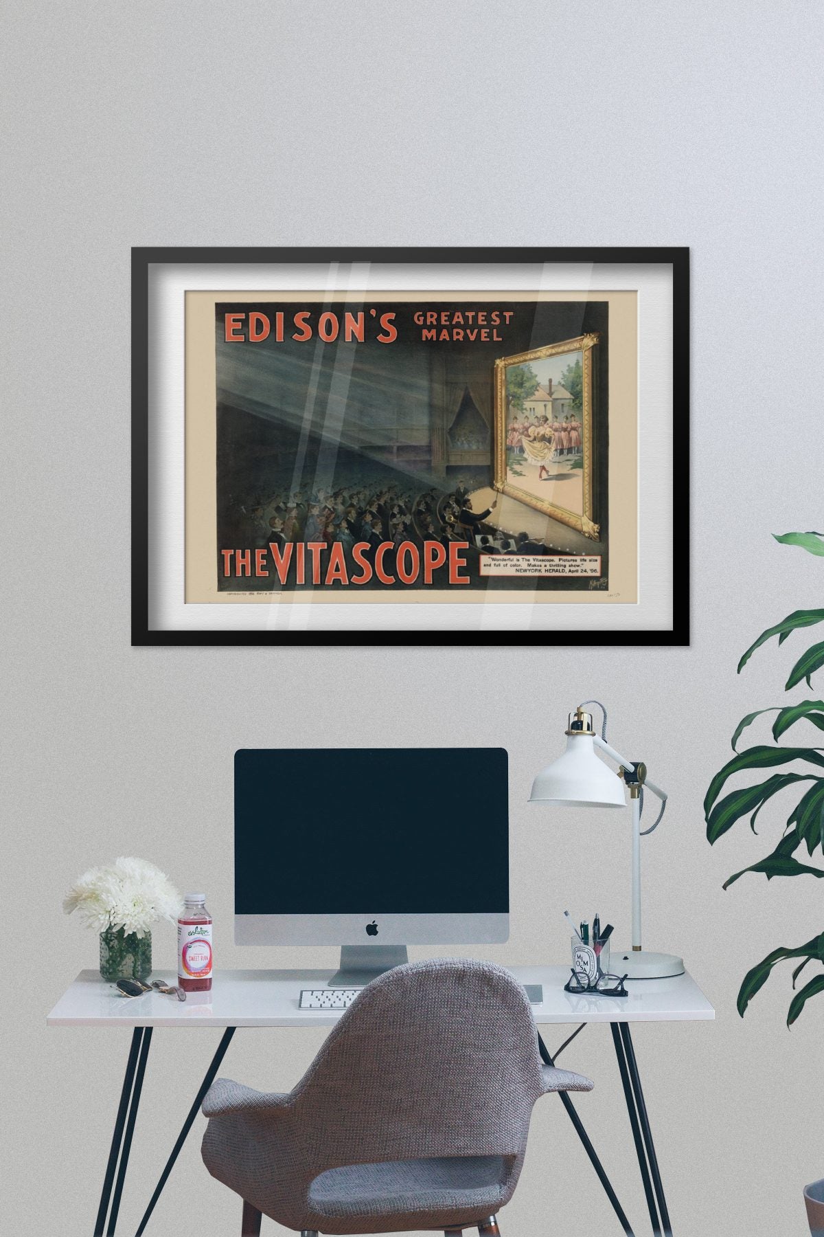 Edisons Vitascope poster framed on a grey wall above a desk
