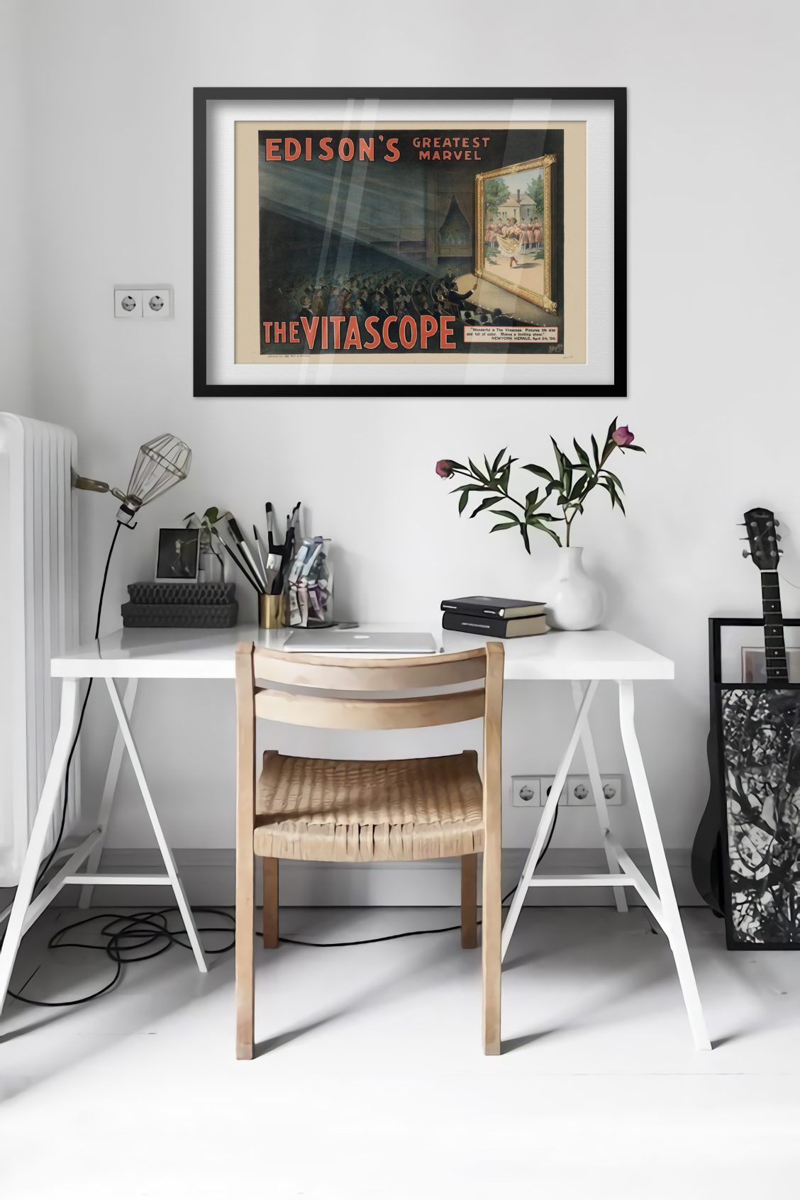 Edisons Vitascope poster framed above a desk in a bright white room