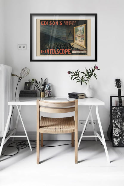 Edisons Vitascope poster framed above a desk in a bright white room