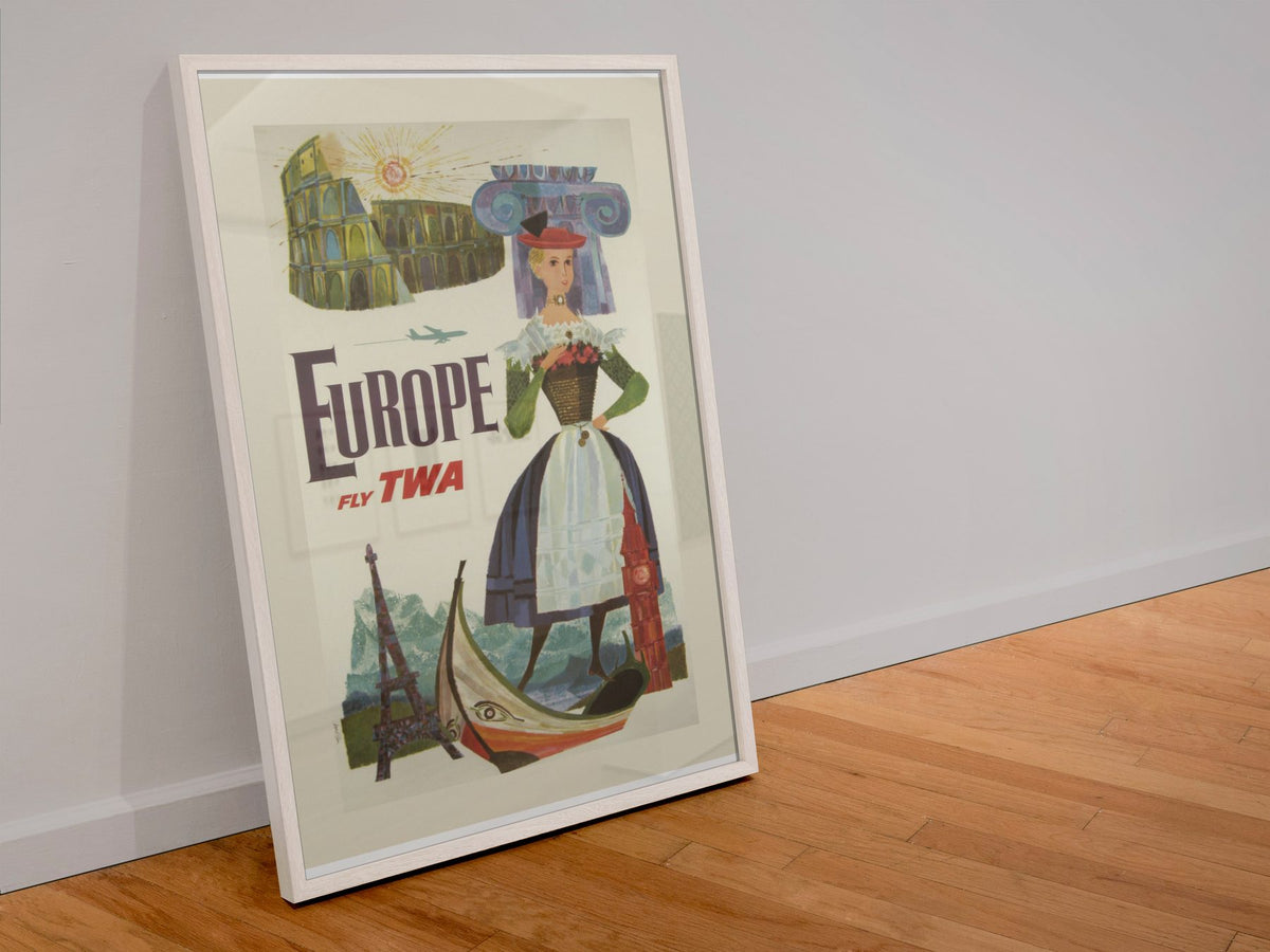 Europe Fly TWA poster in a white frame leaning against a wall
