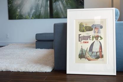 Europe Fly TWA poster leaning beside a blue sofa