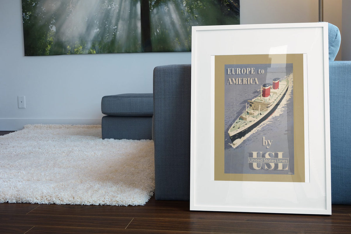 Europe to America United States Lines poster leaning beside a blue sofa