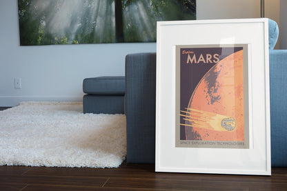 Explore Mars retro space travel poster in a white frame leaning beside a blue sofa