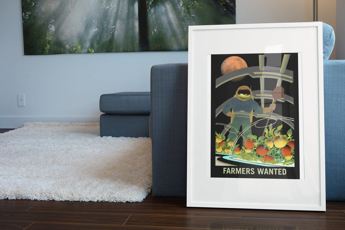 Farmers Wanted on Mars poster in a white frame leaning beside a blue sofa