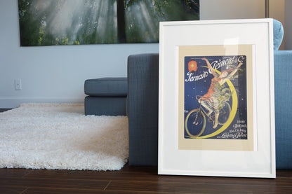 Fernand Clement Cycles poster leaning beside a blue sofa
