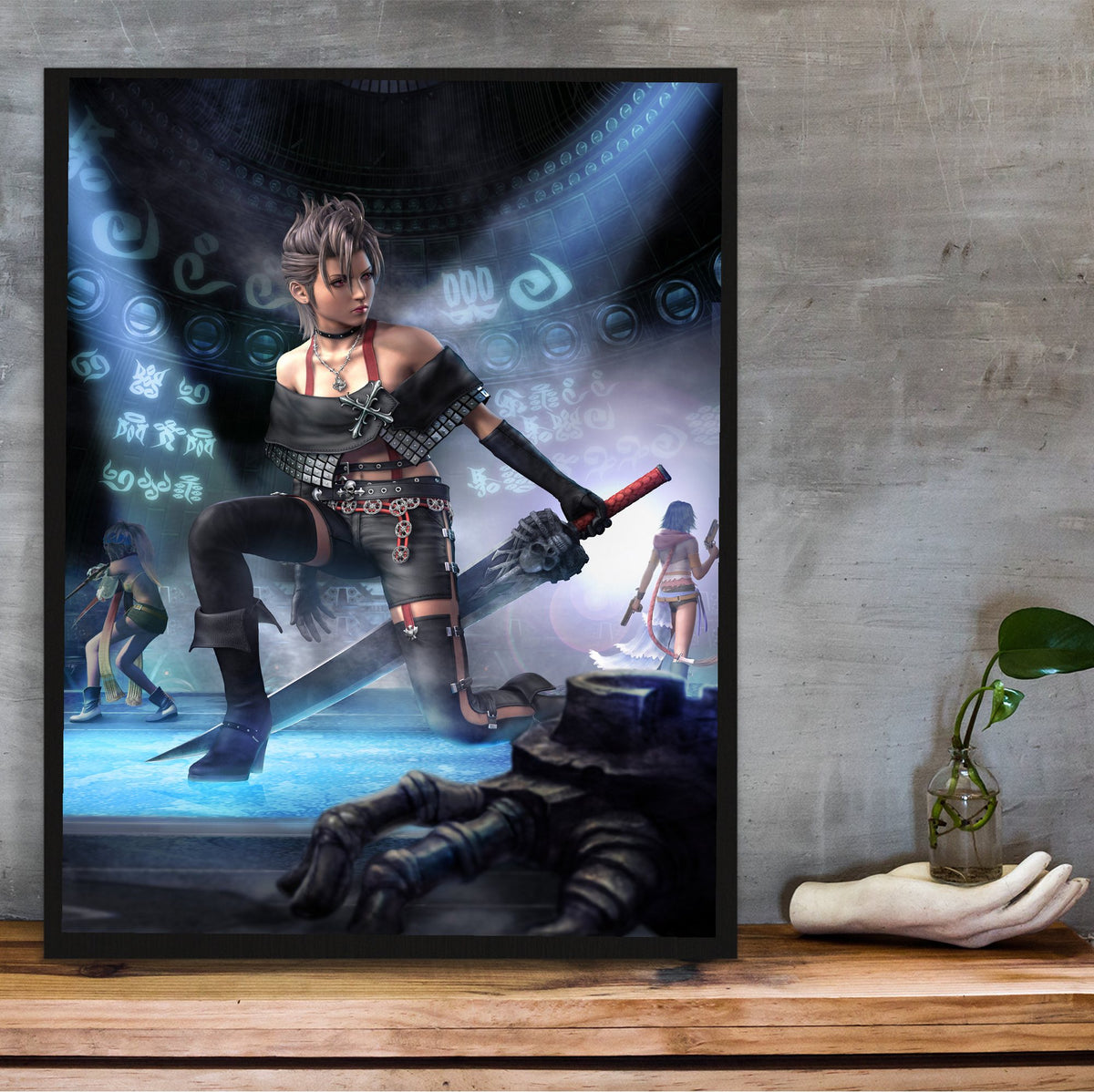 Final Fantasy X-2 Paine Key Art poster in a black frame on a wooden shelf against concrete