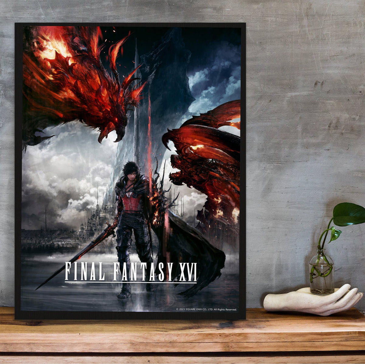 Final Fantasy XVI Key Art poster in a black frame on a wooden shelf against concrete