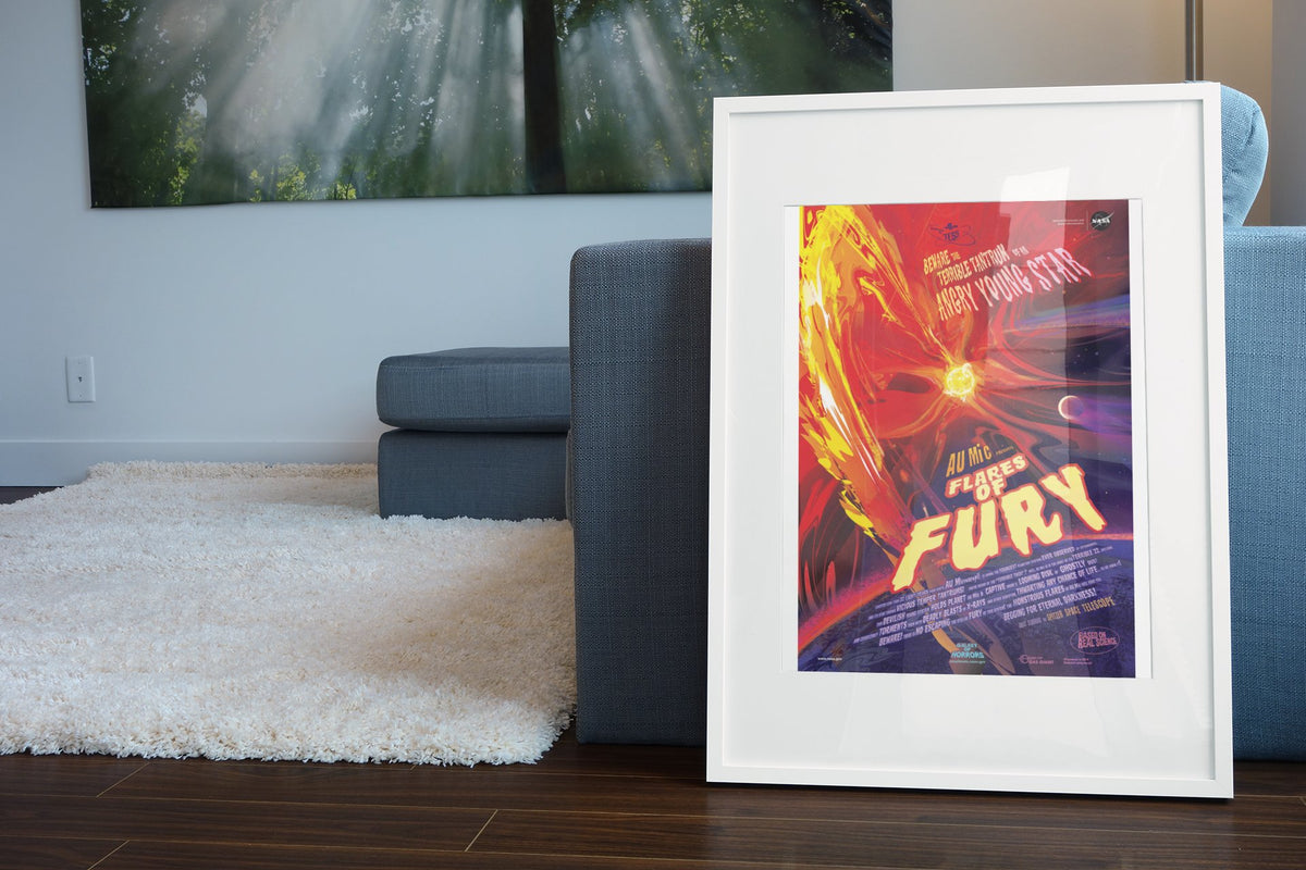 Flares of Fury, NASA Galaxy of Horrors poster in a white frame leaning beside a blue sofa