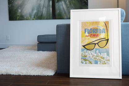 Florida Fly TWA poster leaning beside a blue sofa