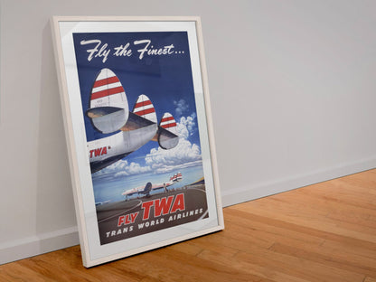 Fly the Finest Fly TWA poster in a white frame leaning against a wall