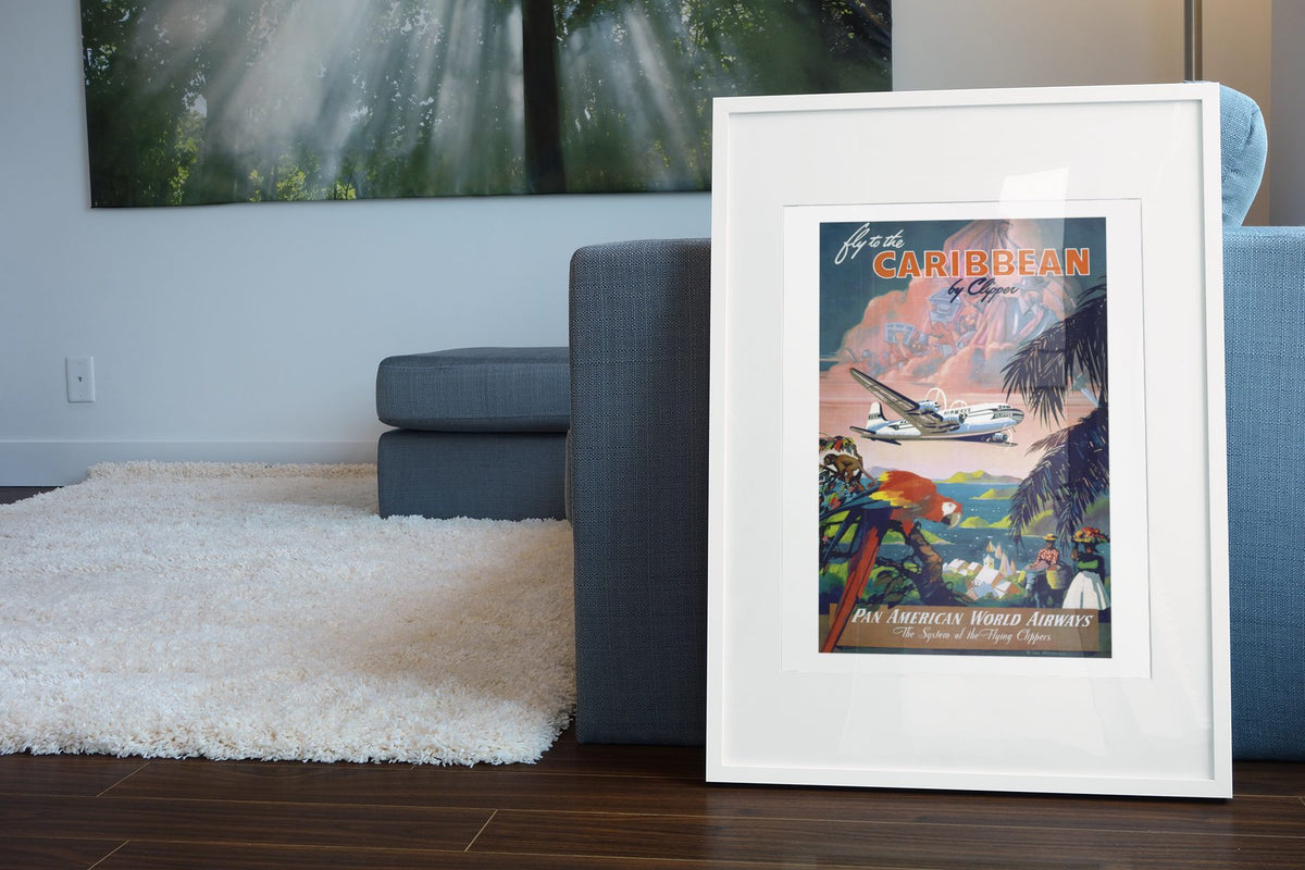 Fly to the Caribbean by Clipper Pan American poster leaning beside a blue sofa