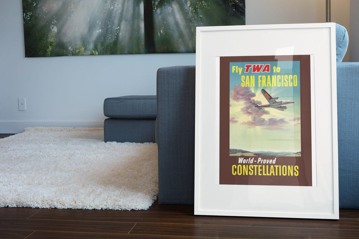 Fly TWA to San Francisco Constellations poster leaning beside a blue sofa