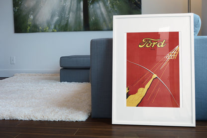 Ford V8 1933 poster in a white frame leaning beside a blue sofa