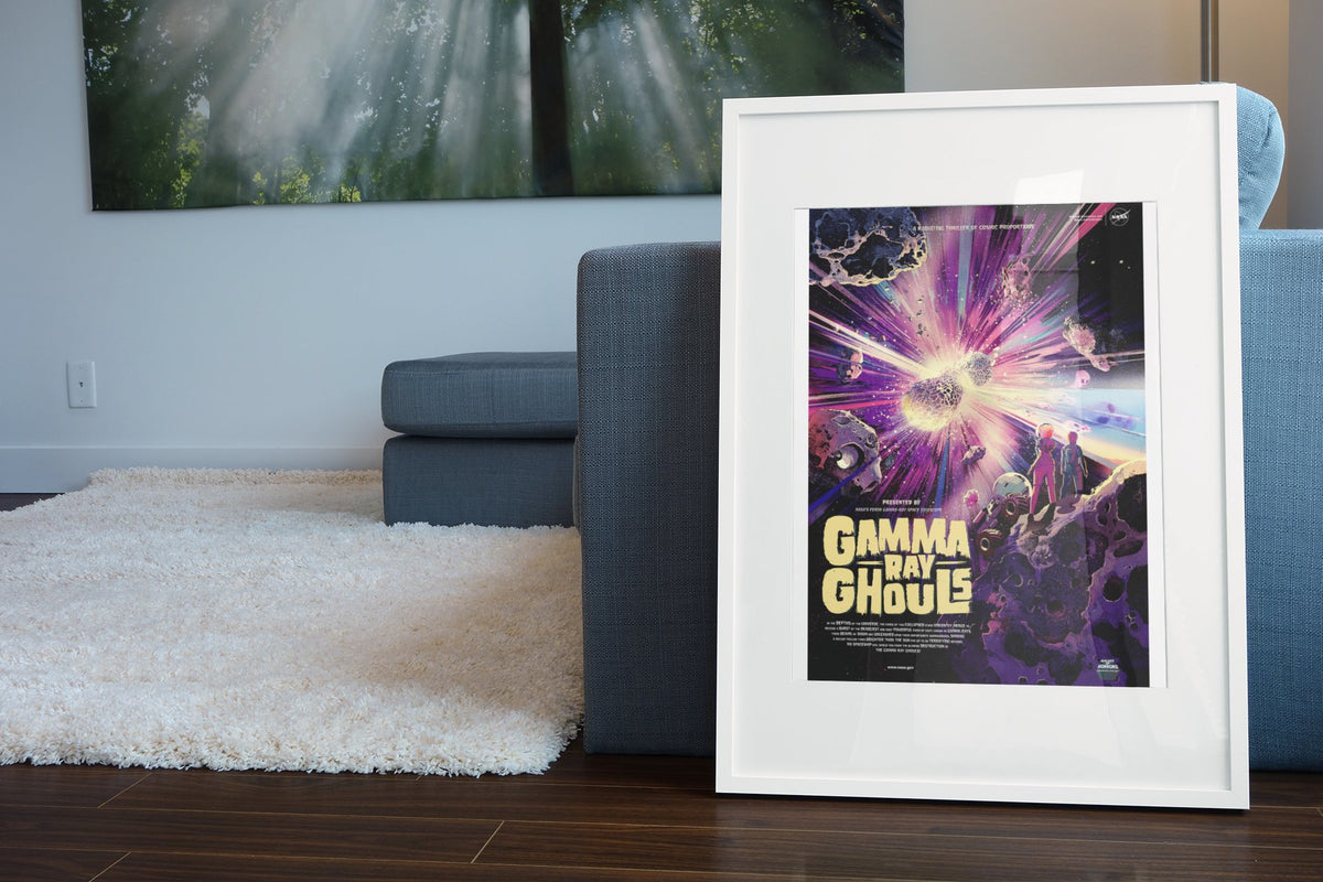 Gamma Ray Ghouls, NASA Galaxy of Horrors poster in a white frame leaning beside a blue sofa