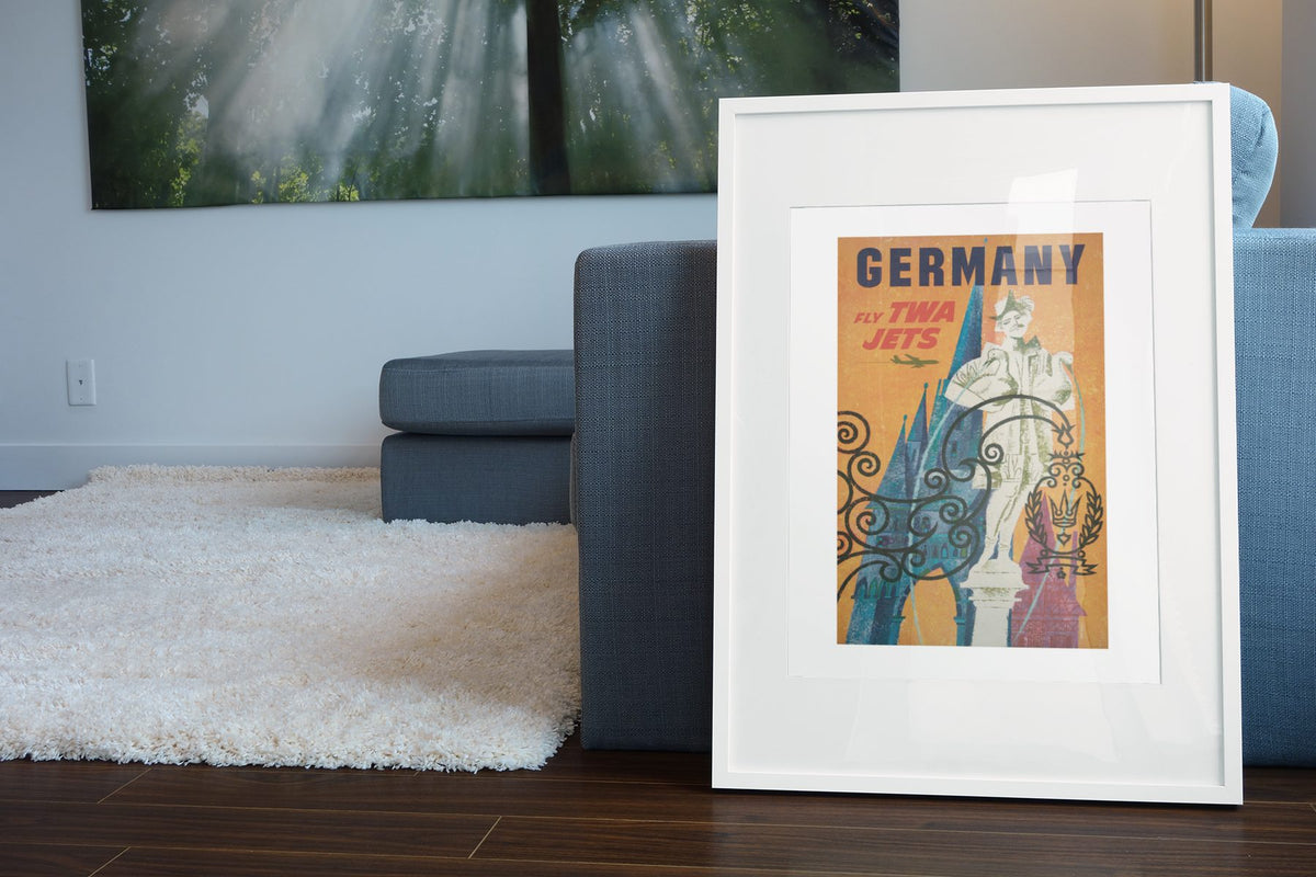 Germany Fly TWA poster leaning beside a blue sofa