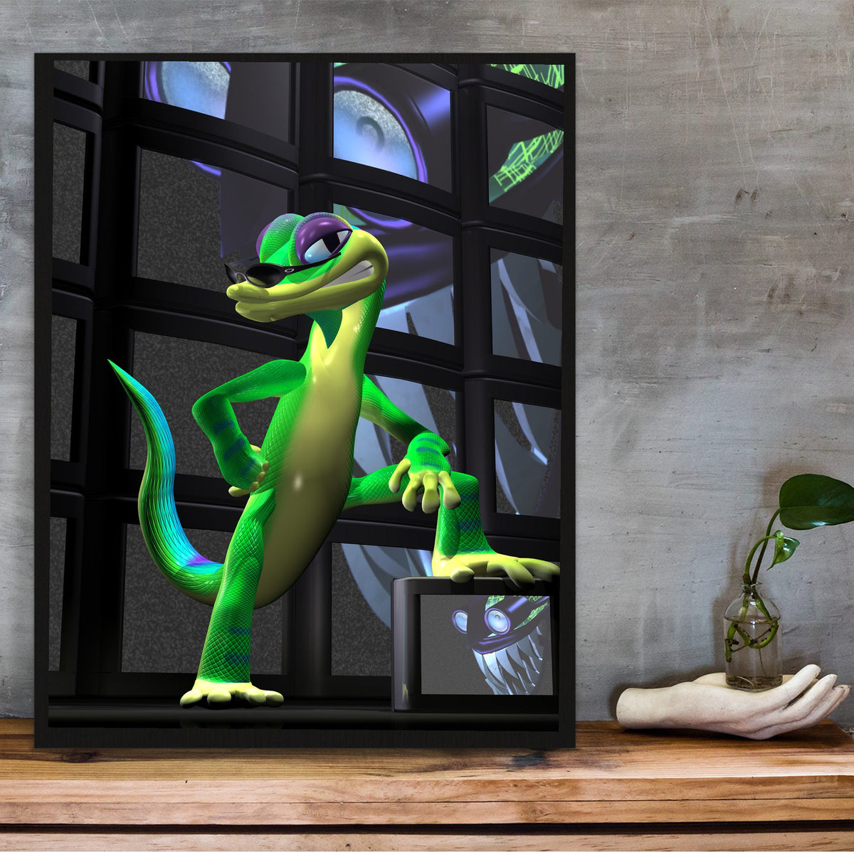 Gex: Enter the Gecko TV Wall Art poster in a black frame on a wooden shelf against concrete