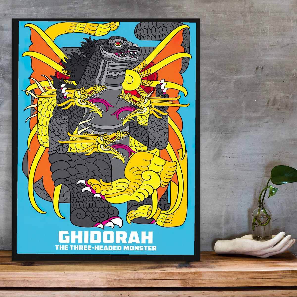 Ghidorah, the Three-Headed Monster (1964) Movie Illustrated Art poster in a black frame on a wooden shelf against concrete