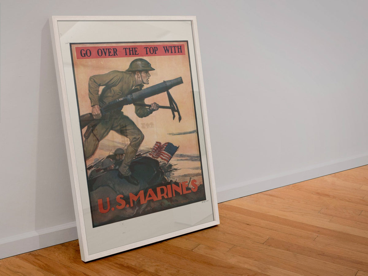 Go Over the Top with U.S. Marines poster in a white frame leaning against a wall