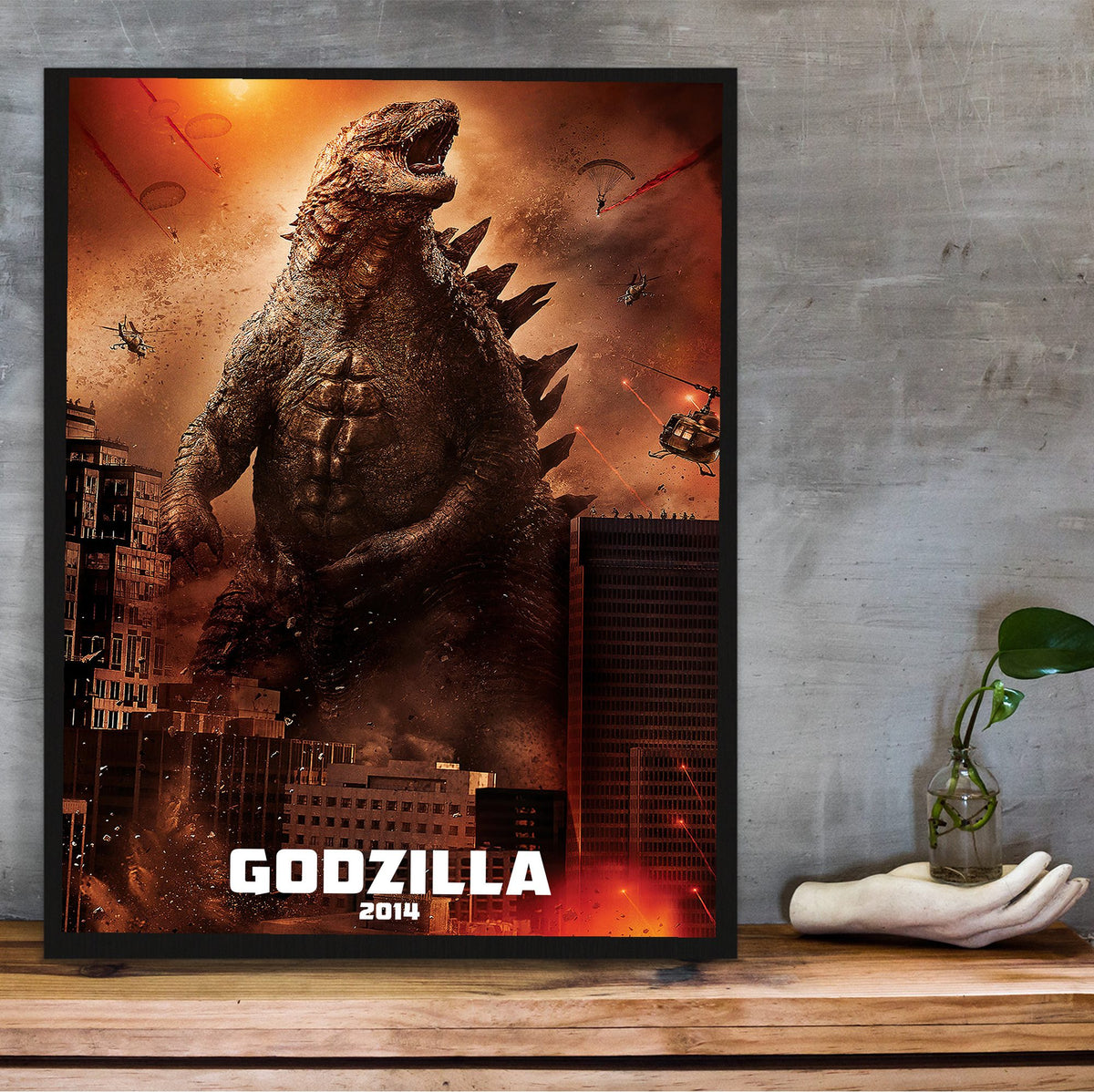 Godzilla (2014) Movie Key Art poster in a black frame on a wooden shelf against concrete