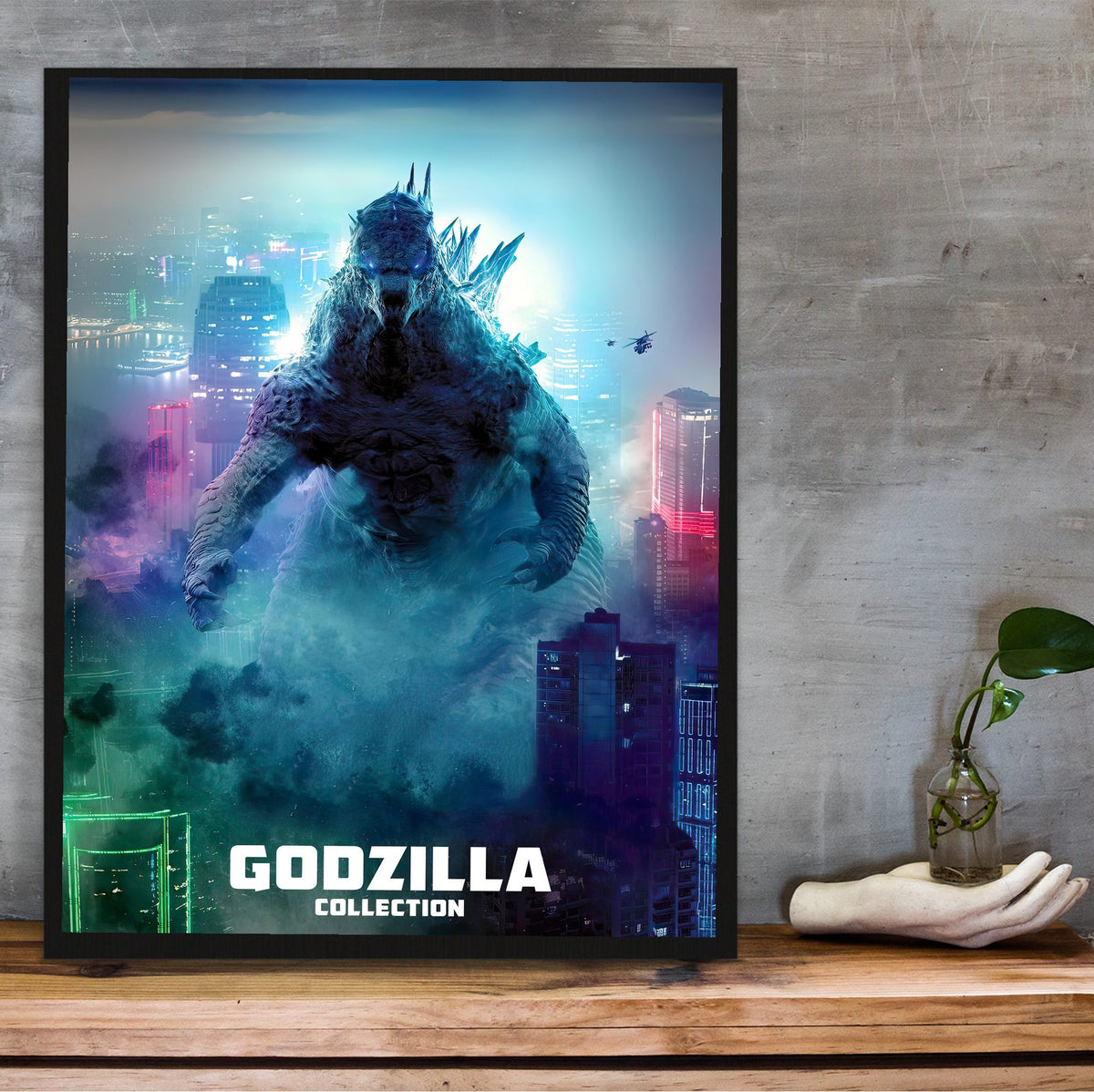 Godzilla Complete Collection Movie Art poster in a black frame on a wooden shelf against concrete
