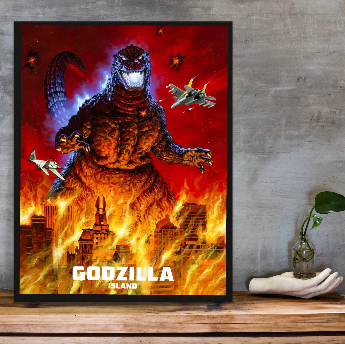 Godzilla Island (1997) Key Art poster in a black frame on a wooden shelf against concrete