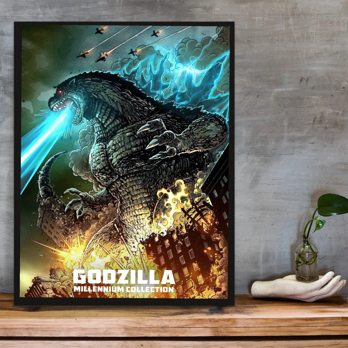 Godzilla Millennium Era Movie Collection Art poster in a black frame on a wooden shelf against concrete