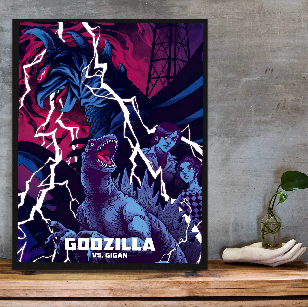 Godzilla vs. Gigan (1972) Movie Illustrated Art poster in a black frame on a wooden shelf against concrete