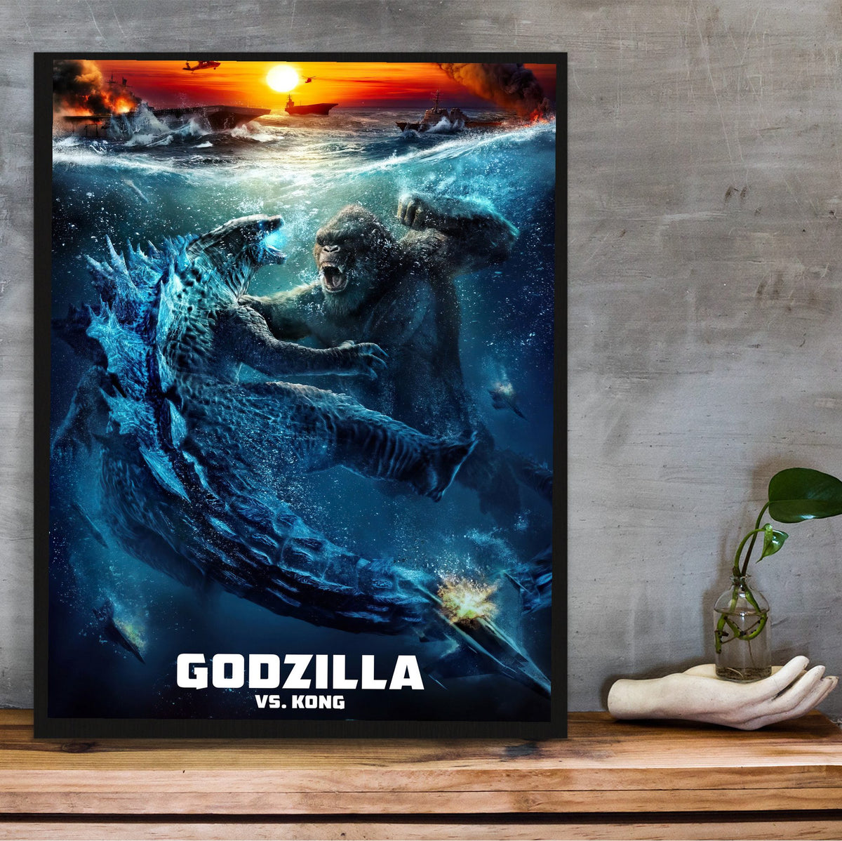 Godzilla vs. Kong (2021) Movie Ocean Battle Art poster in a black frame on a wooden shelf against concrete