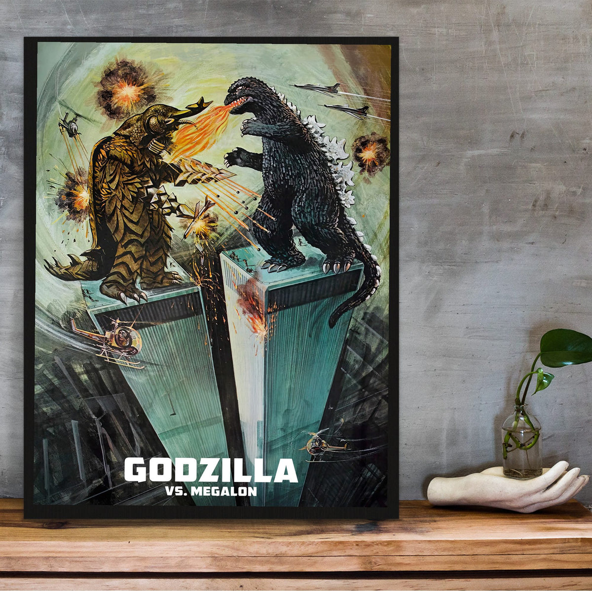 Godzilla vs. Megalon (1973) Movie Illustrated Art poster in a black frame on a wooden shelf against concrete