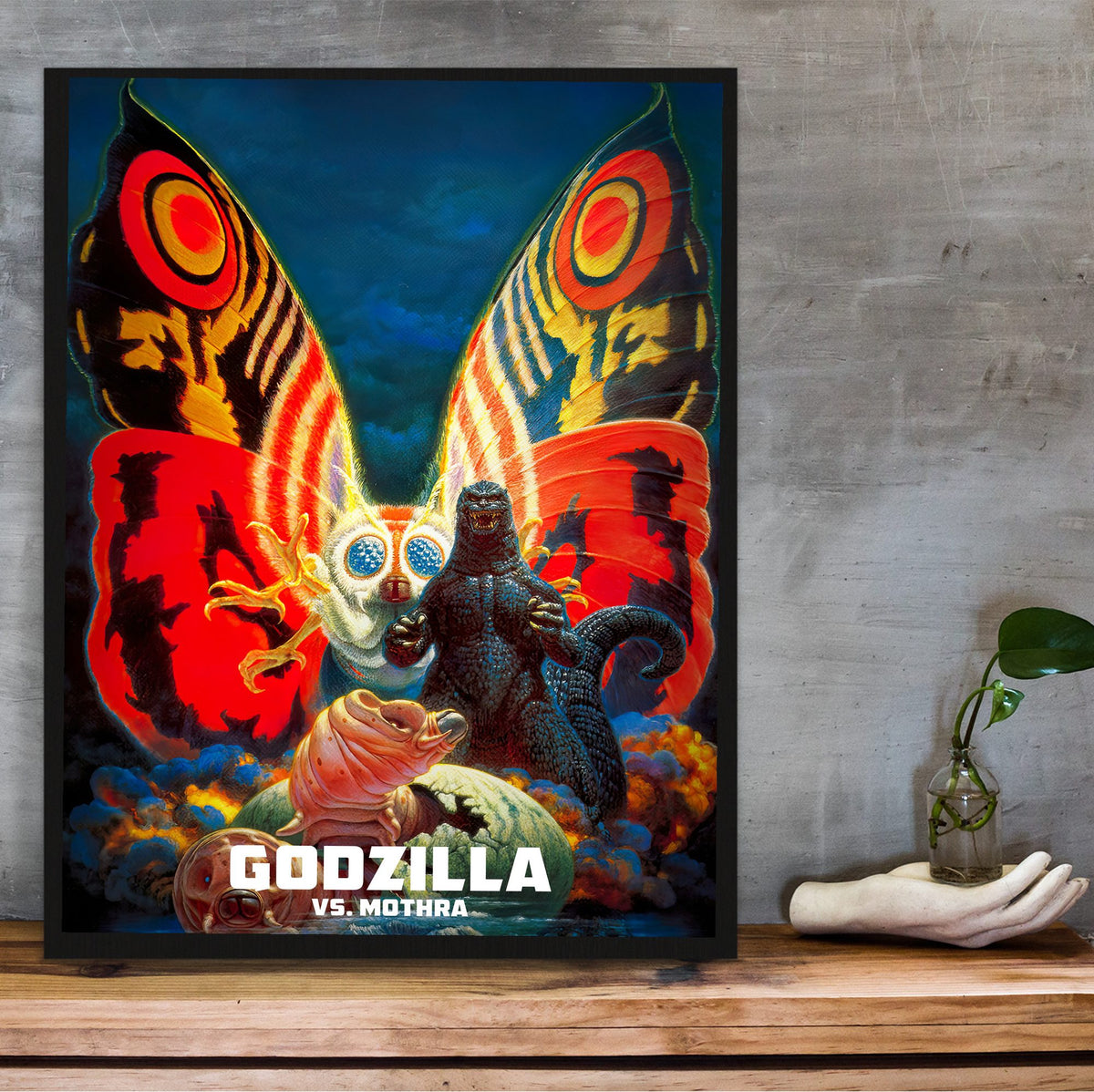 Godzilla vs. Mothra (1992) Movie Key Art poster in a black frame on a wooden shelf against concrete