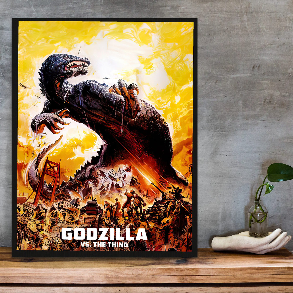 Godzilla vs. The Thing (1964) Movie Illustrated Art poster in a black frame on a wooden shelf against concrete
