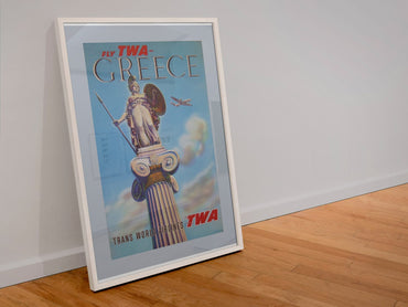 Greece Fly TWA 1955 poster in a white frame leaning against a wall