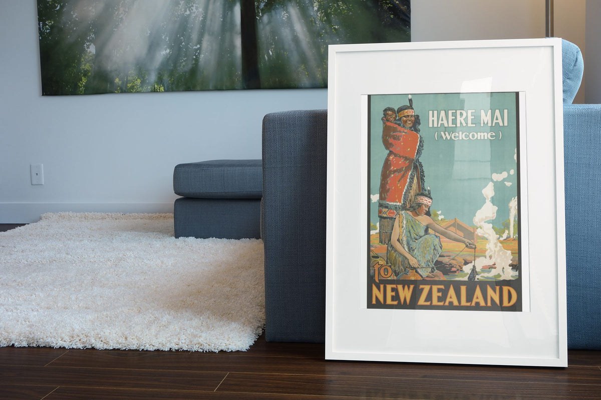 Haere Mai Welcome to New Zealand poster leaning beside a blue sofa