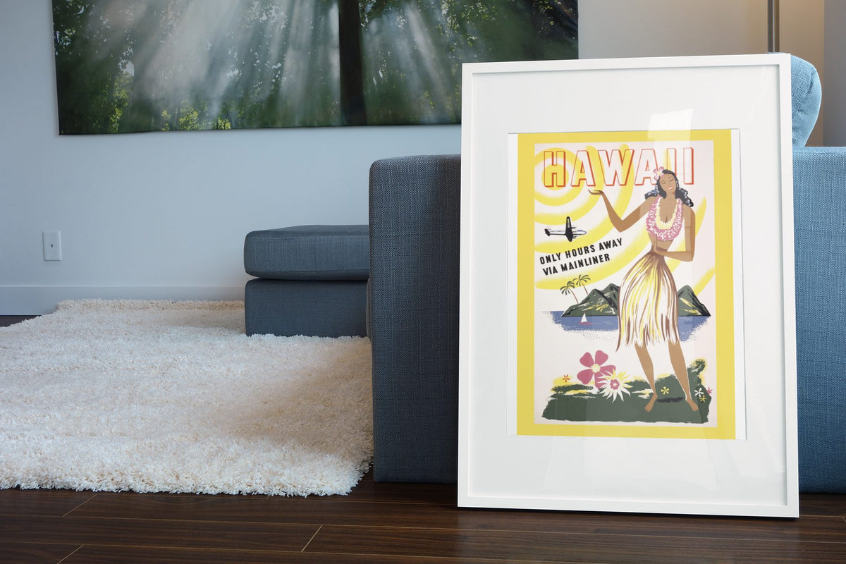Hawaii via Mainliner poster leaning beside a blue sofa
