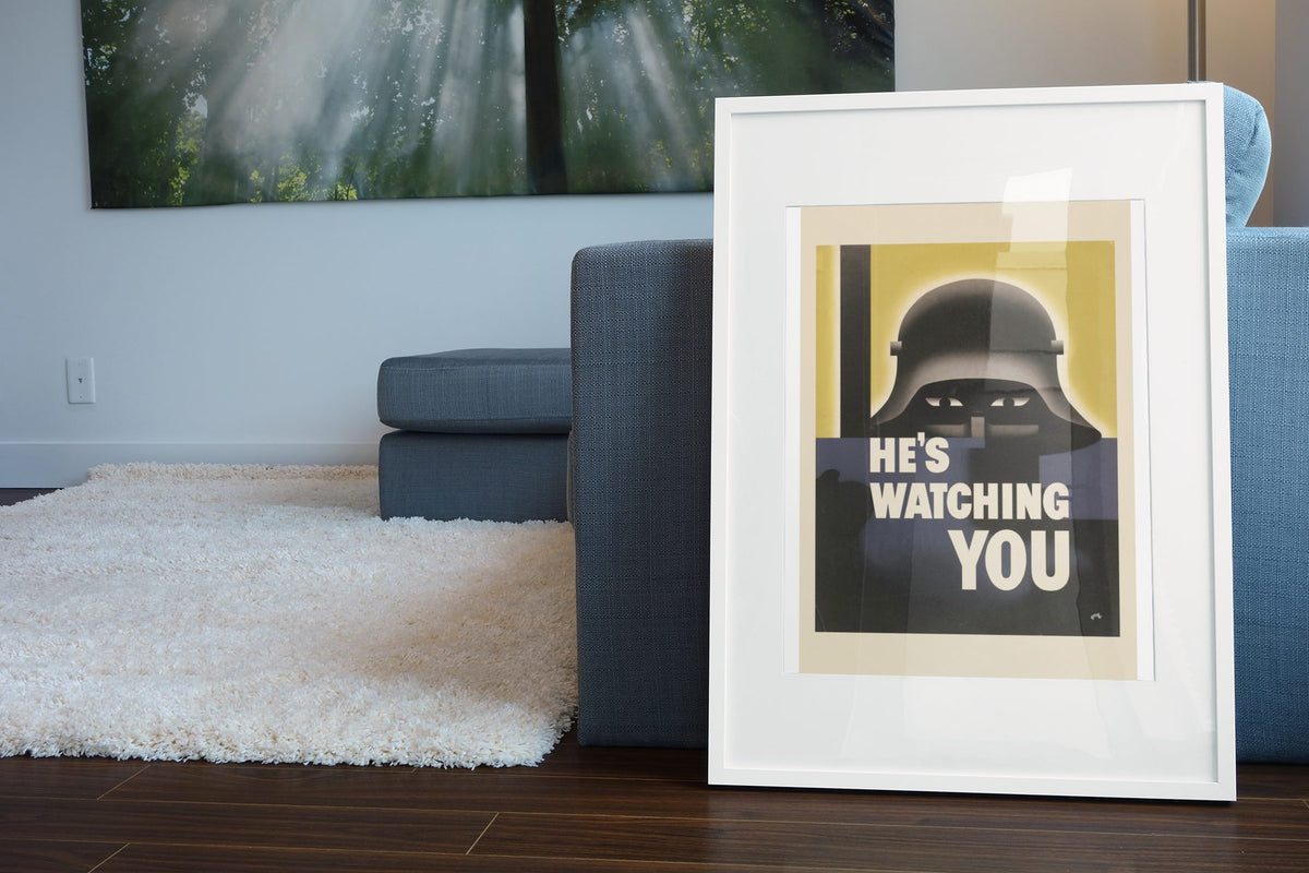Hes Watching You poster leaning beside a blue sofa