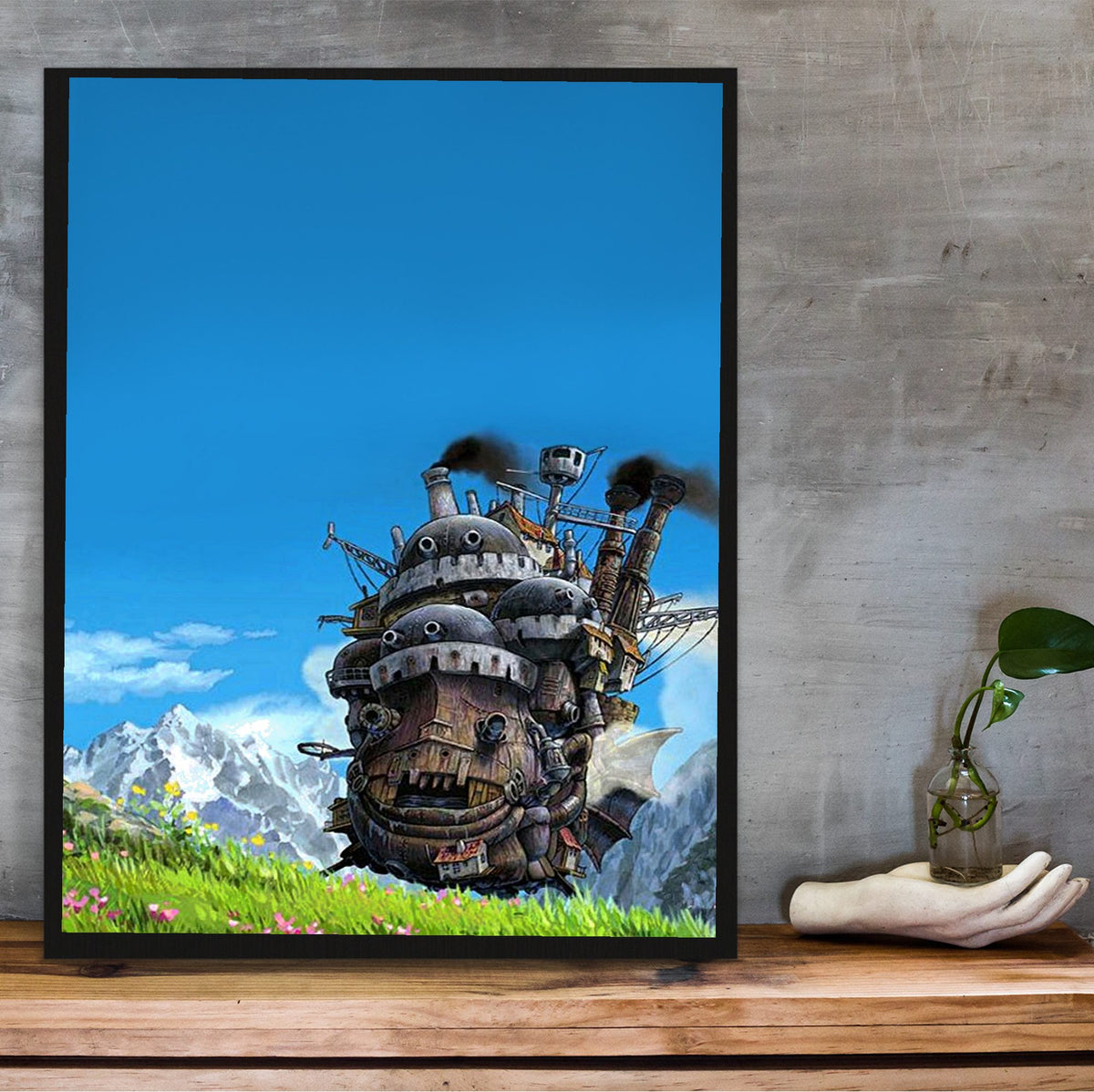Howl's Moving Castle Triptych Panel Art poster in a black frame on a wooden shelf against concrete