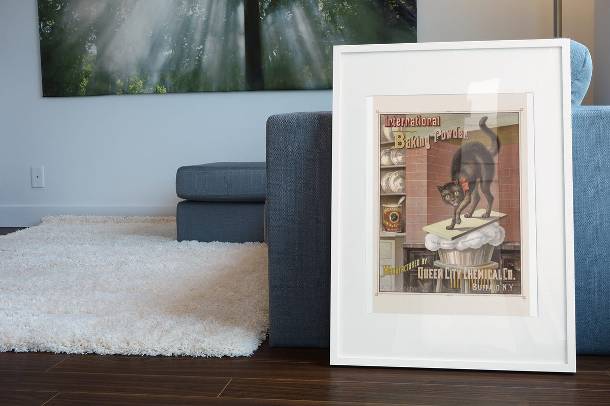 International Baking Powder Black Cat poster leaning beside a blue sofa