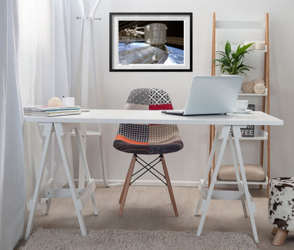 International Space Station over Earth poster framed above a white desk