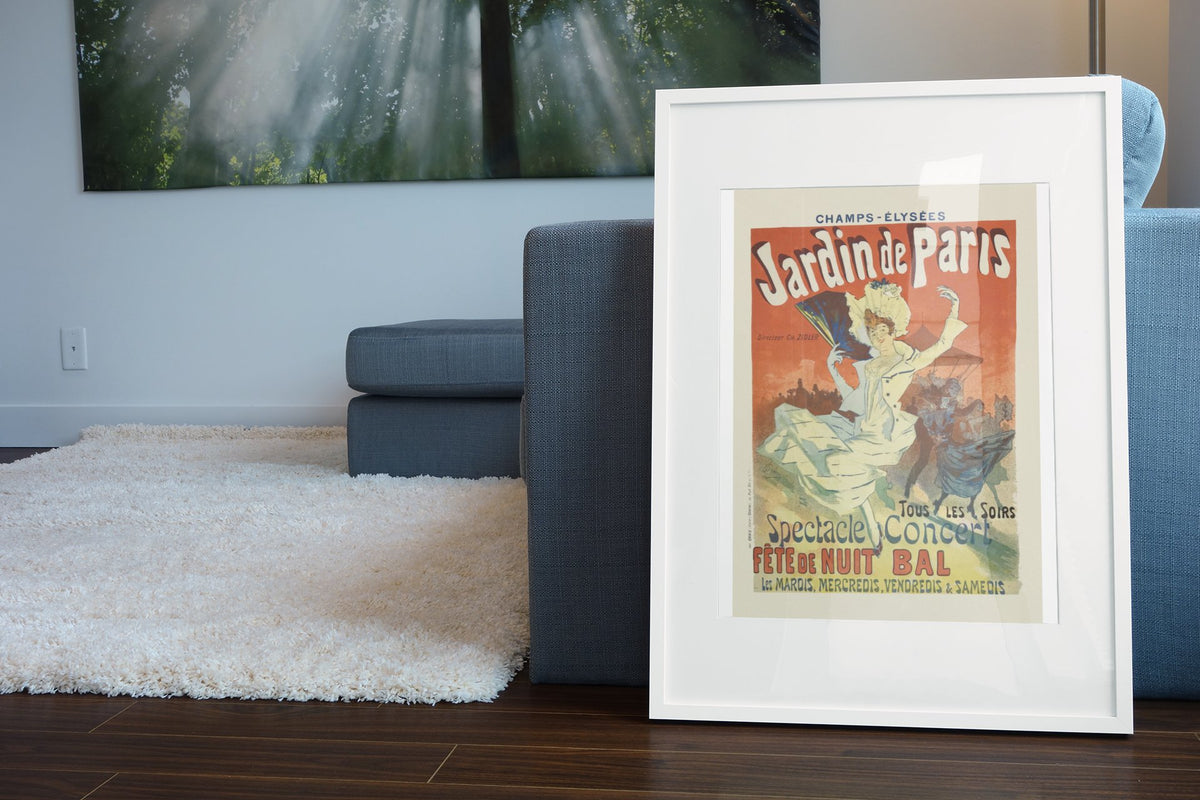 Jardin de Paris 1897 poster in a white frame leaning beside a blue sofa