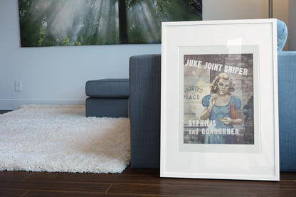 Juke Joint Sniper poster leaning beside a blue sofa