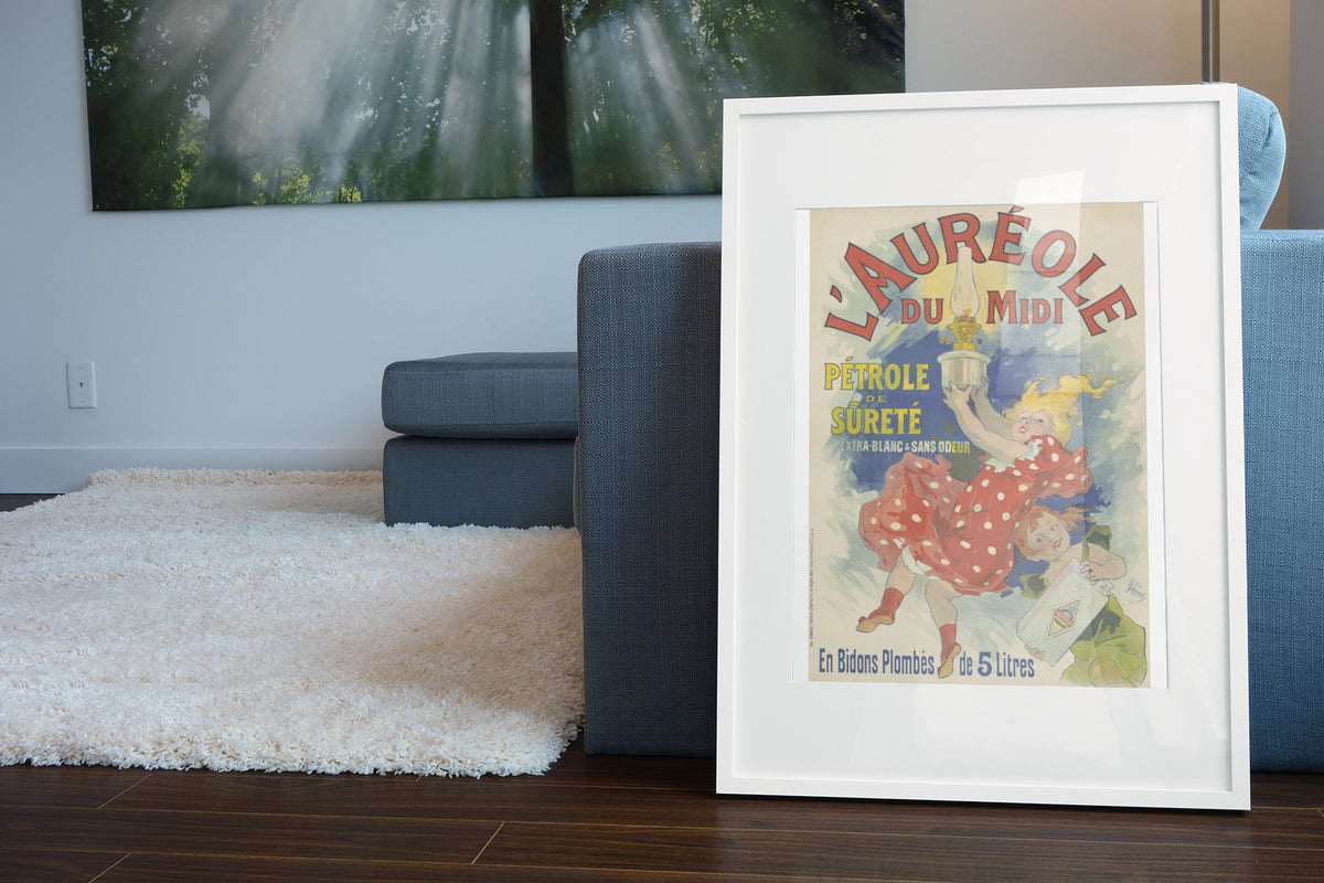 Jules Chéret L'Auréole du Midi poster in a white frame leaning beside a blue sofa